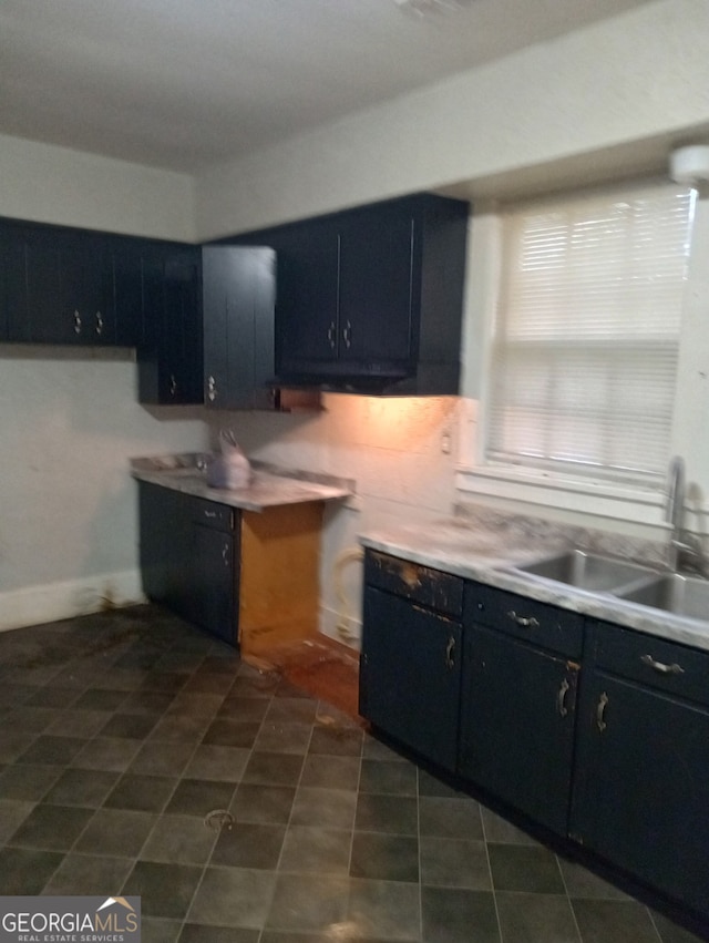 kitchen featuring dark cabinets, light countertops, and a sink