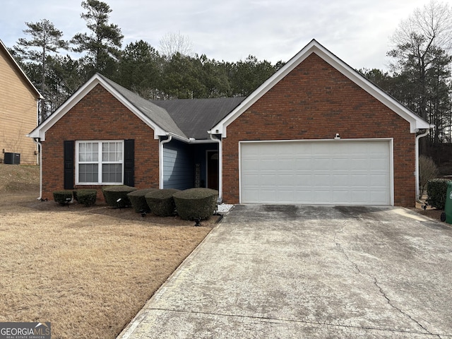 view of front of house with an attached garage, cooling unit, concrete driveway, and brick siding