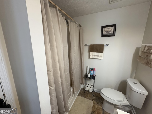 bathroom featuring a textured ceiling, stone finish flooring, and toilet