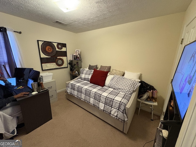 bedroom with baseboards, visible vents, light carpet, and a textured ceiling