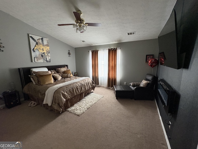 bedroom featuring visible vents, lofted ceiling, ceiling fan, a textured ceiling, and carpet flooring