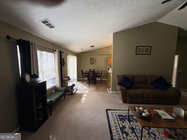 living area with lofted ceiling, a textured ceiling, carpet, and visible vents