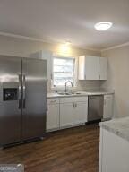 kitchen with light countertops, appliances with stainless steel finishes, a sink, and white cabinetry