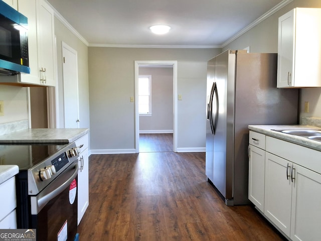 kitchen with appliances with stainless steel finishes, white cabinets, light countertops, and ornamental molding