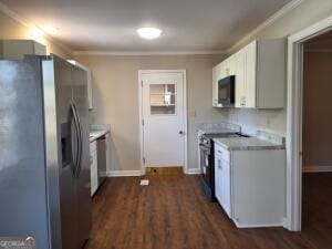 kitchen with white cabinets, dark wood-style flooring, stainless steel appliances, crown molding, and light countertops