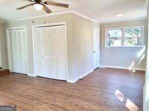 unfurnished bedroom with dark wood-style floors, ornamental molding, and baseboards