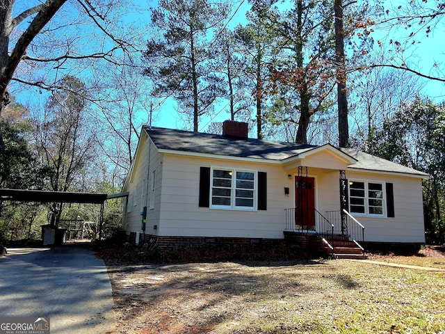 view of front of property with a carport, driveway, and a chimney