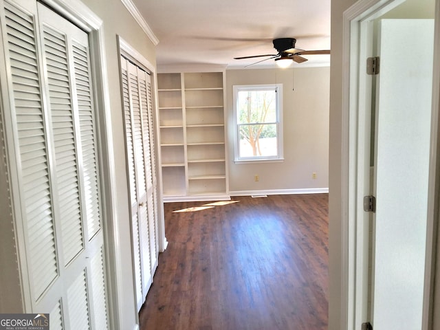 interior space with ornamental molding, dark wood finished floors, and baseboards