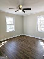 empty room with ceiling fan, baseboards, and dark wood finished floors