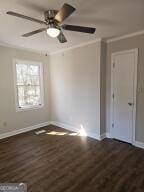 unfurnished room with dark wood-style flooring, crown molding, and baseboards