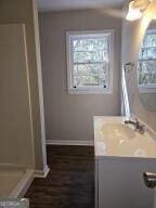 full bath featuring vanity, baseboards, and walk in shower