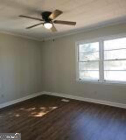 empty room with baseboards, ornamental molding, ceiling fan, and dark wood-style flooring