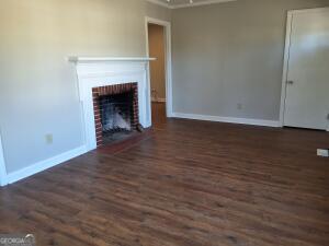 unfurnished living room featuring a fireplace, baseboards, and dark wood-type flooring