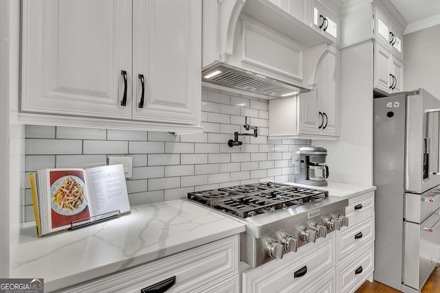 kitchen with decorative backsplash, white cabinets, custom range hood, appliances with stainless steel finishes, and light stone counters