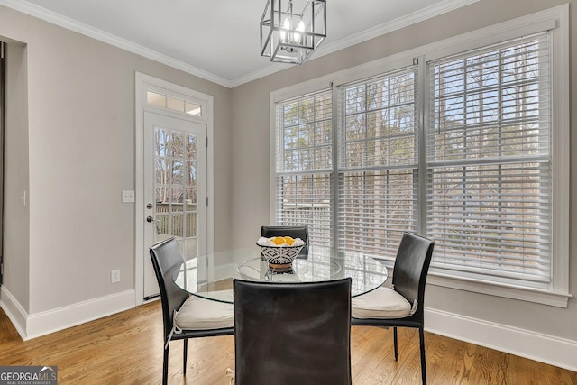 dining area featuring light wood finished floors, baseboards, ornamental molding, and a notable chandelier