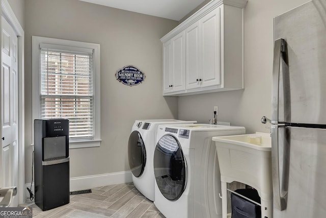 clothes washing area with washing machine and dryer, a sink, visible vents, baseboards, and cabinet space