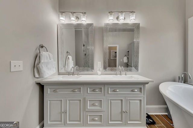 full bath featuring double vanity, a freestanding tub, baseboards, and a sink