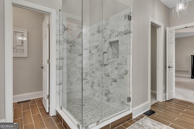 bathroom with a stall shower, wood tiled floor, visible vents, and baseboards