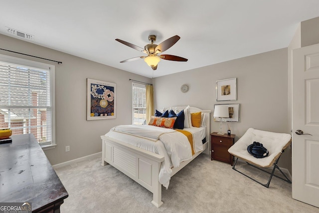 bedroom featuring baseboards, multiple windows, visible vents, and light colored carpet