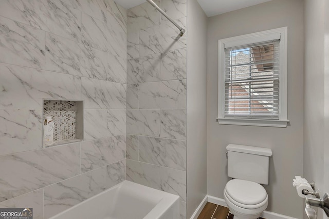 bathroom with tub / shower combination, wood finished floors, toilet, and baseboards