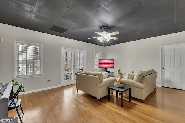 living room with baseboards, a ceiling fan, a drop ceiling, wood finished floors, and french doors