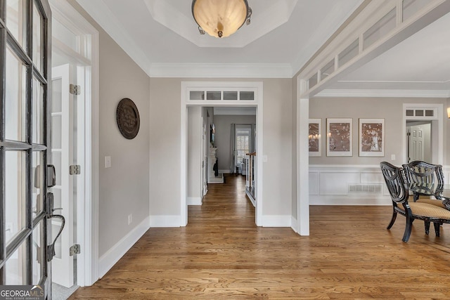 foyer featuring baseboards, visible vents, wood finished floors, and ornamental molding