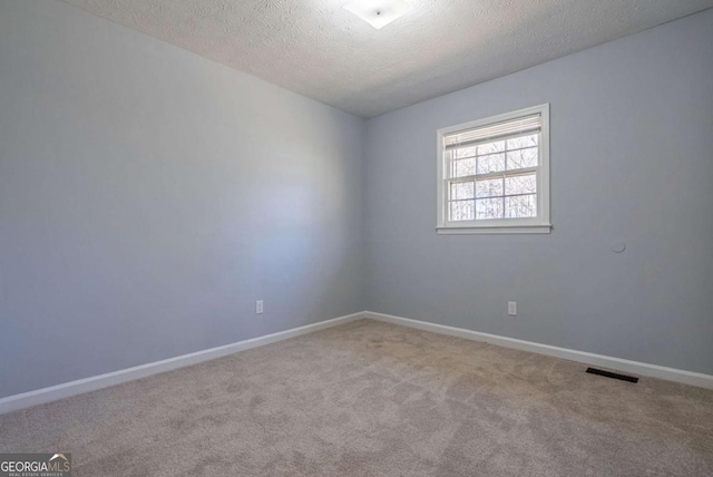 carpeted spare room with visible vents, a textured ceiling, and baseboards