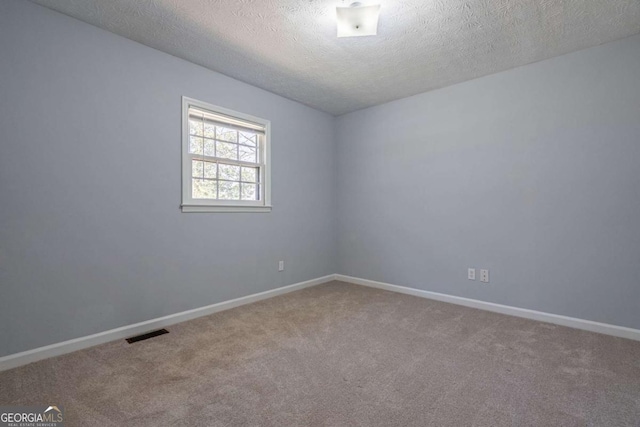 carpeted empty room featuring baseboards, visible vents, and a textured ceiling