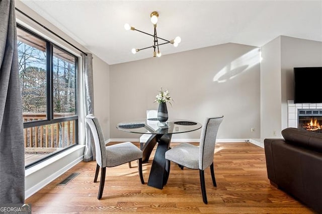 dining room with baseboards, visible vents, vaulted ceiling, and wood finished floors