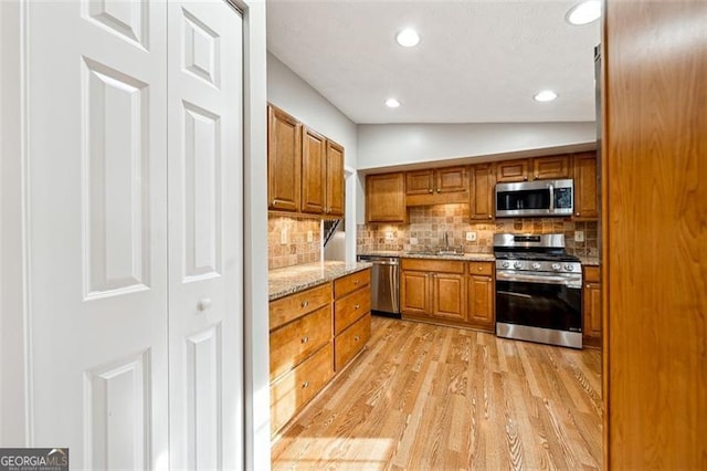 kitchen with light wood-style flooring, appliances with stainless steel finishes, and brown cabinets