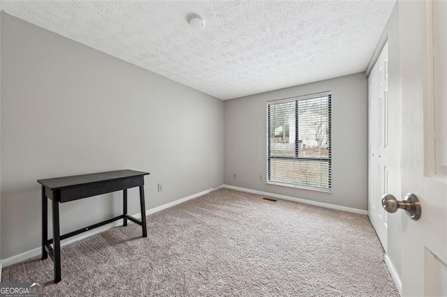 carpeted empty room with a textured ceiling and baseboards