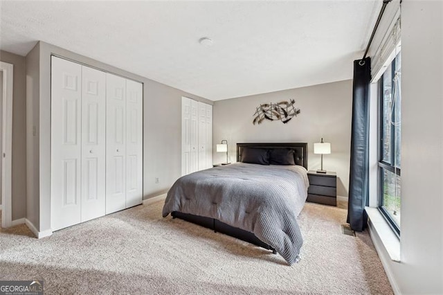 carpeted bedroom featuring multiple closets and baseboards