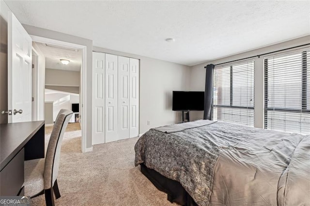 bedroom with a textured ceiling, a closet, and light colored carpet