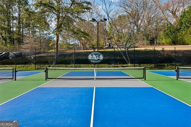 view of tennis court with community basketball court and fence