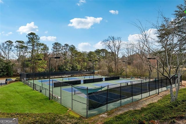 view of tennis court featuring fence and a lawn