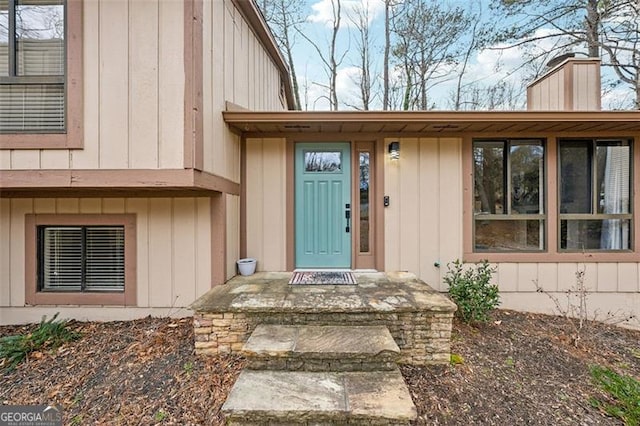 doorway to property featuring a chimney and board and batten siding