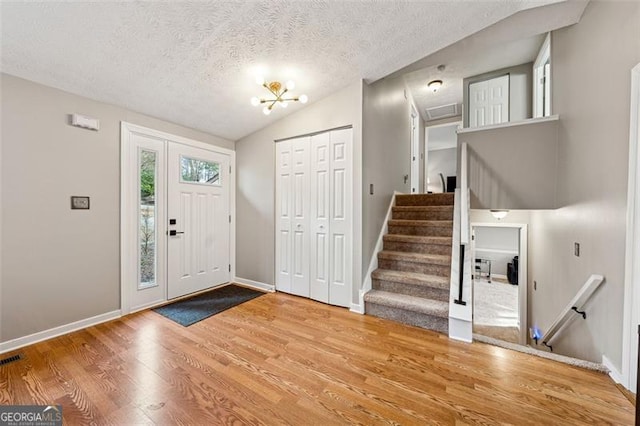 entrance foyer featuring vaulted ceiling, a textured ceiling, wood finished floors, and baseboards