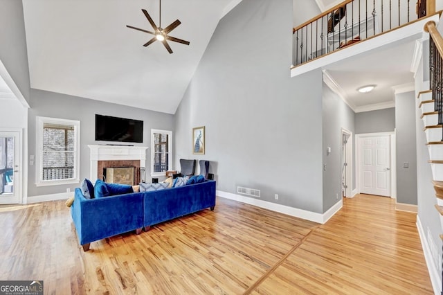 living area with visible vents, a brick fireplace, ceiling fan, wood finished floors, and high vaulted ceiling