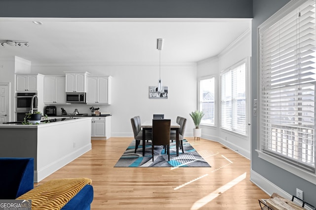 dining space with baseboards, light wood-style floors, a chandelier, and crown molding