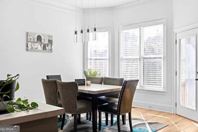 dining space with light wood finished floors and ornamental molding