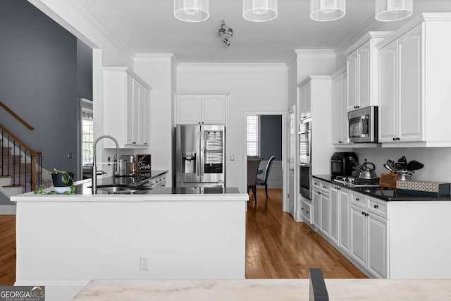 kitchen featuring stainless steel appliances, dark countertops, pendant lighting, and a sink