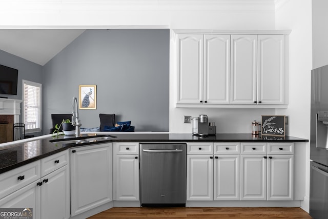 kitchen featuring a sink, appliances with stainless steel finishes, light wood-style floors, white cabinetry, and lofted ceiling