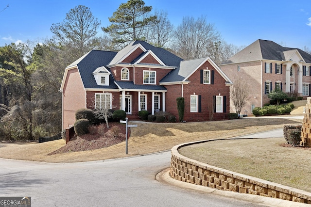 view of front of home featuring brick siding, a front lawn, and curved driveway