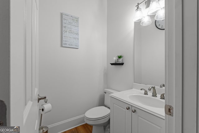 bathroom with toilet, baseboards, wood finished floors, and vanity