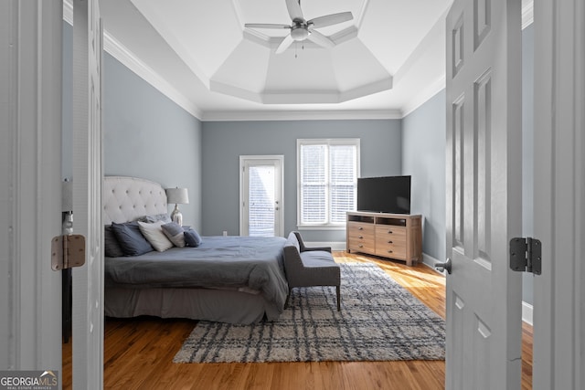 bedroom with baseboards, a raised ceiling, crown molding, ceiling fan, and wood finished floors