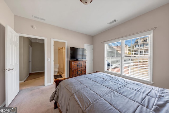 bedroom with light colored carpet, visible vents, baseboards, and ensuite bathroom