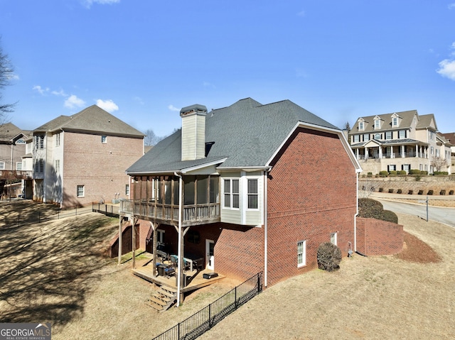 back of property featuring a patio, a sunroom, a fenced backyard, a residential view, and brick siding