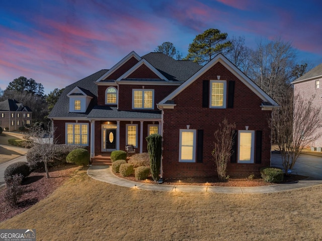 view of front of home with brick siding and a lawn