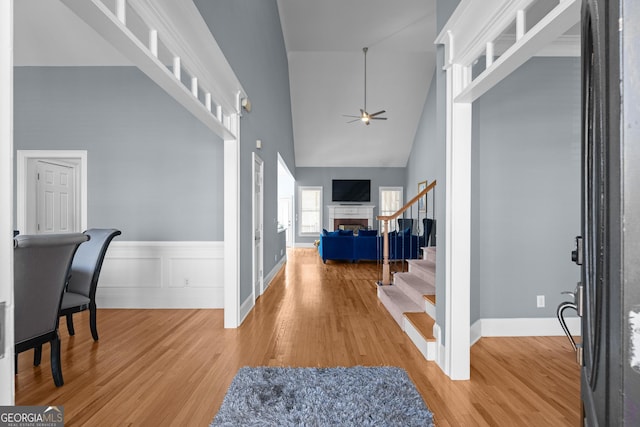 entryway featuring a high ceiling, stairway, a fireplace, and wood finished floors