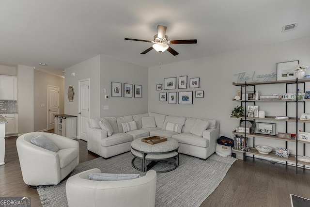 living room featuring a ceiling fan, visible vents, and dark wood finished floors